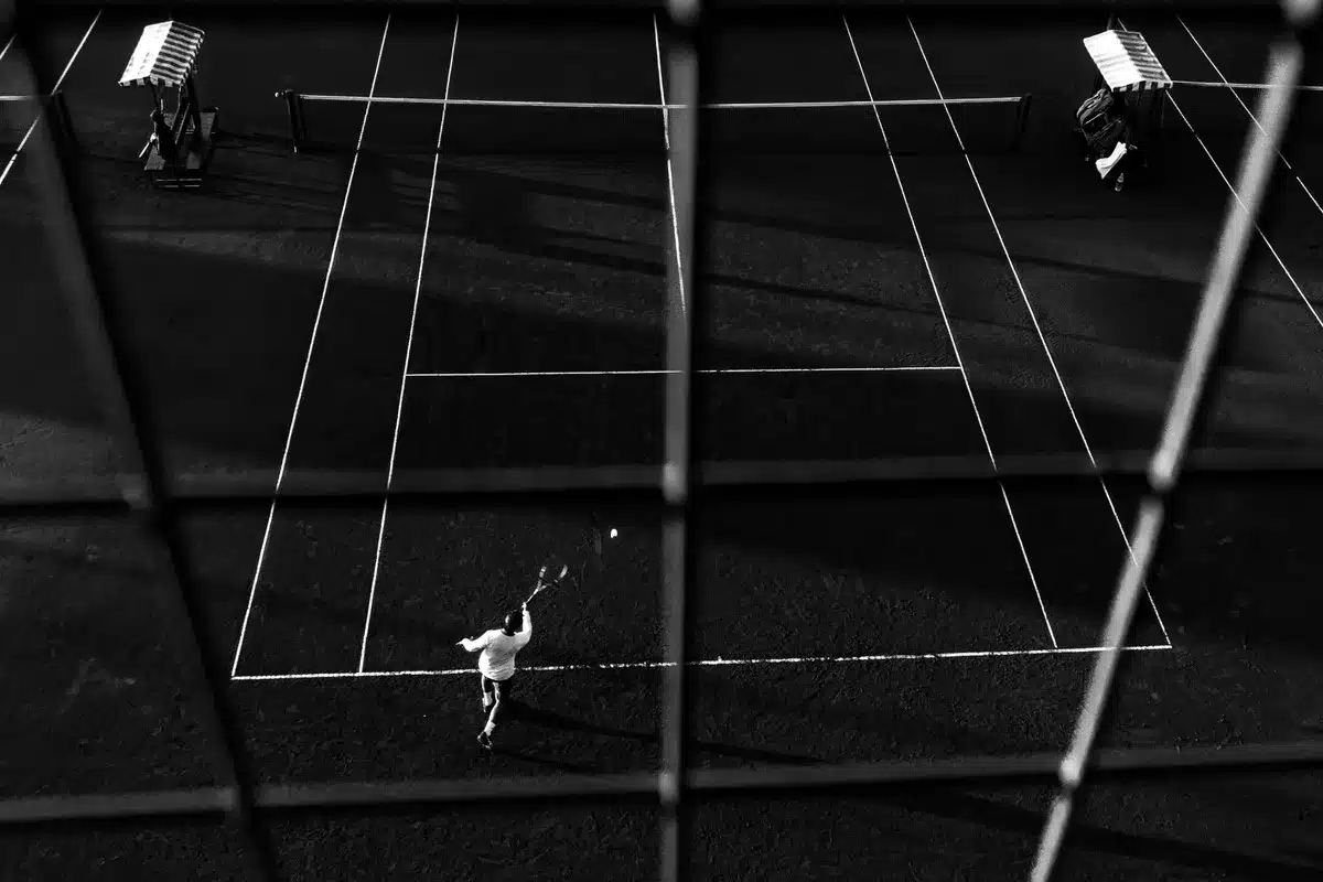 Campo da tennis bagnato dalla pioggia con giocatore che attende il recupero della partita