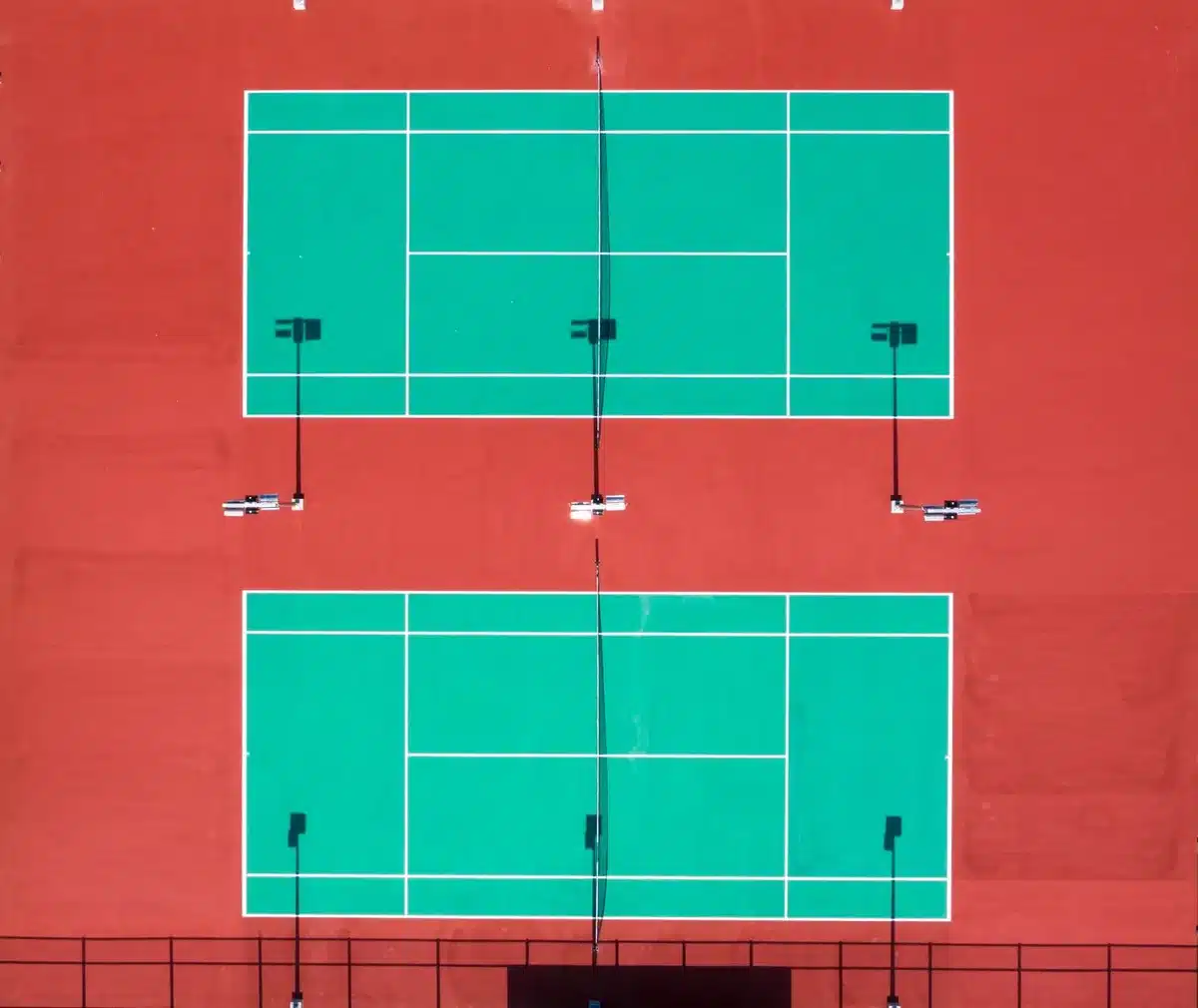 Giocatori di tennis in doppio su campo in cemento durante una partita serale sotto i riflettori dello stadio