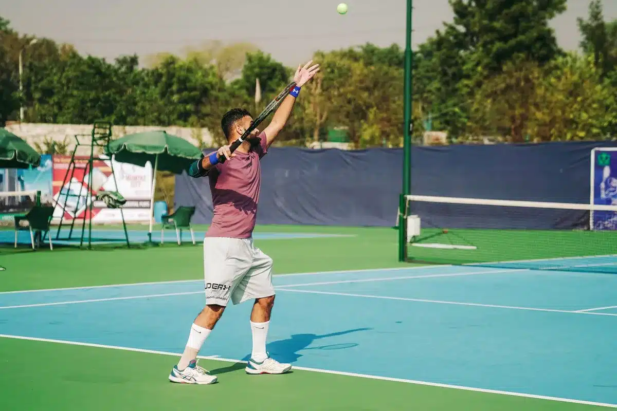 Tennista al servizio durante una partita su campo duro in uno stadio