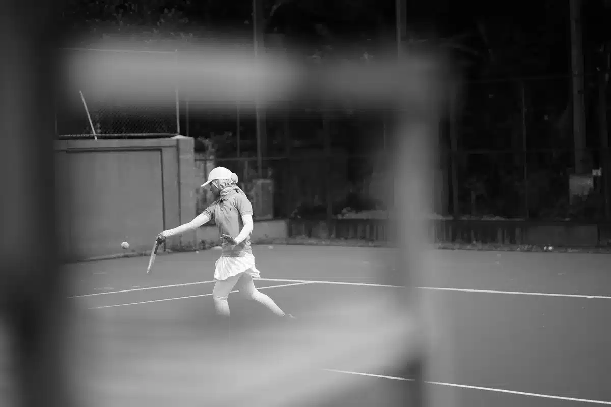 Tennista in allenamento intenso sul campo, concentrata sul lavoro