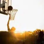 Un giocatore di basket con palla in mano su un parquet di palestra, con determinazione e focus