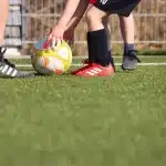 Due silhouette in allenamento su un campo di calcio vuoto, pallone e panchina visibili