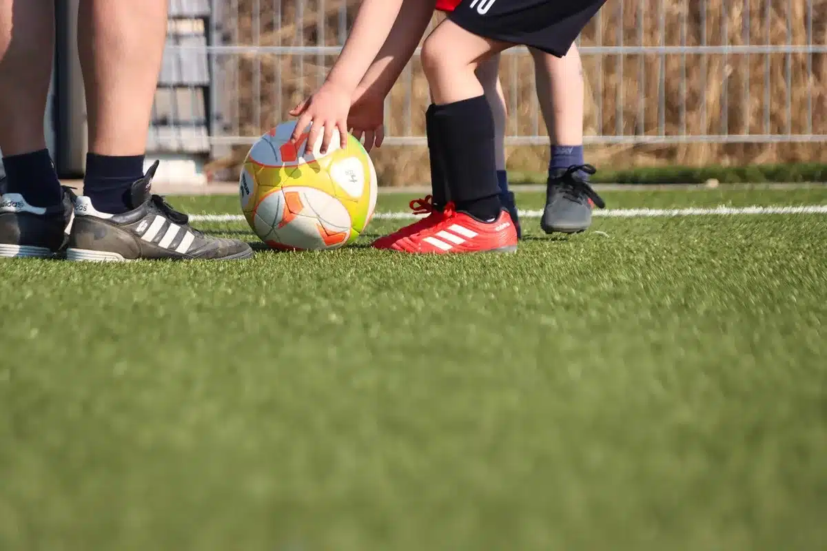 Due silhouette in allenamento su un campo di calcio vuoto, pallone e panchina visibili