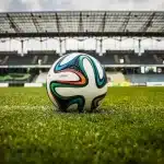 Tunnel di uno stadio con scarpini e fascia da capitano su una panchina, luce in lontananza