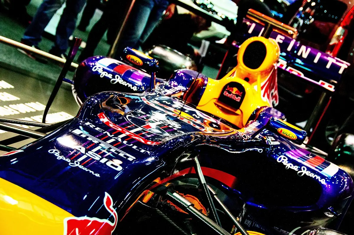 Vettura di F1 ferma in griglia dopo le qualifiche con meccanici sullo sfondo