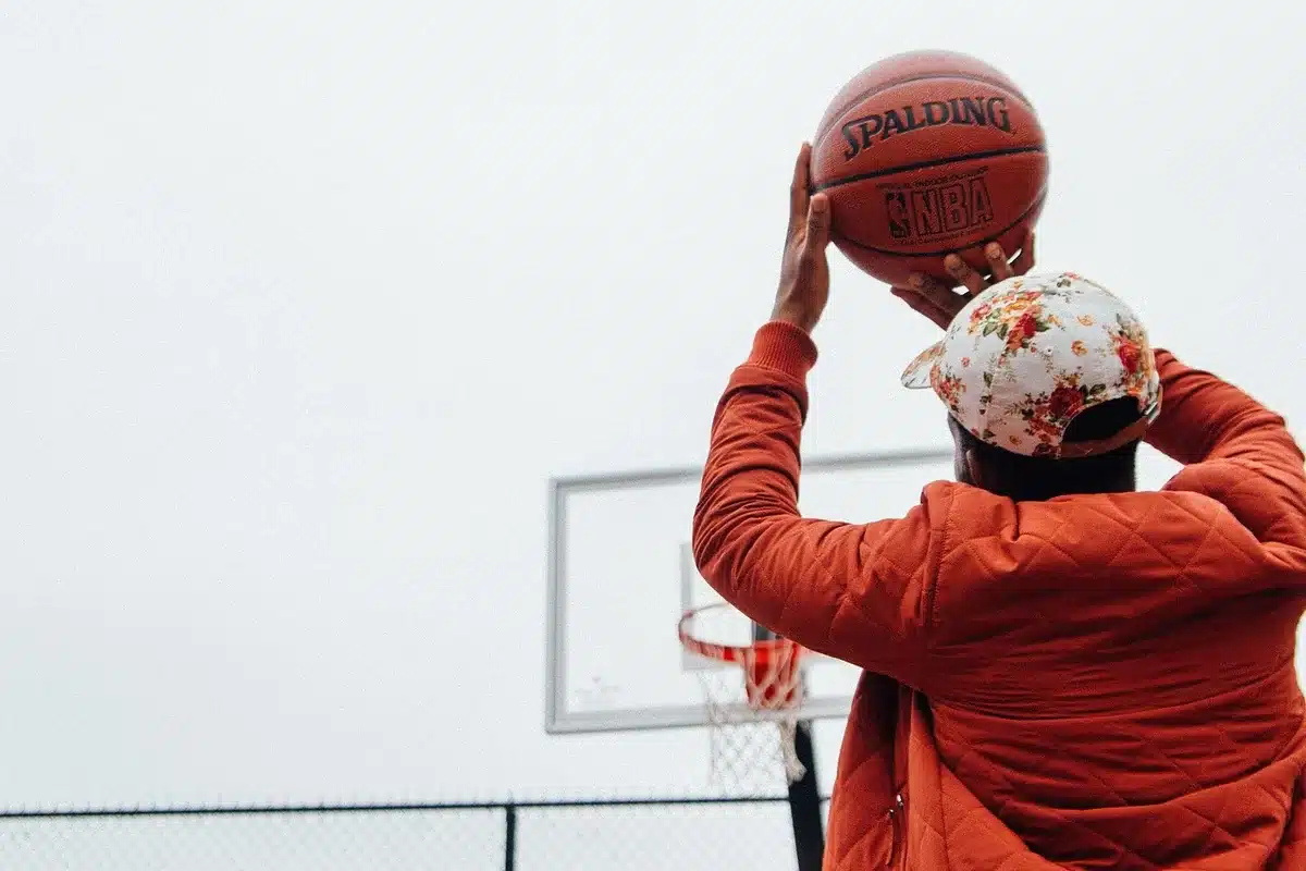 Giocatore di basket in azione di tiro durante una partita, con ritmo e creatività offensiva.