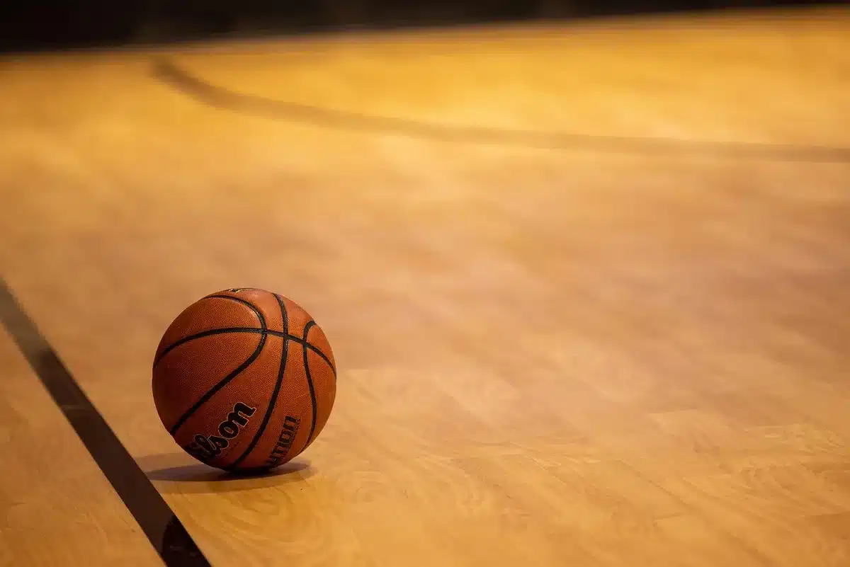 Palestra di basket vuota con scarpe da gioco e palla vicino alla linea dei tre punti