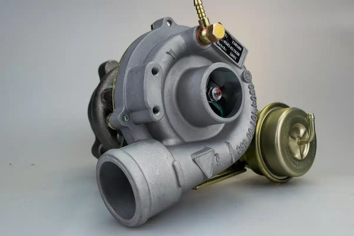 Tecnico regola componenti di un motore turbocompresso in laboratorio F1 con schemi tecnici sullo sfondo
