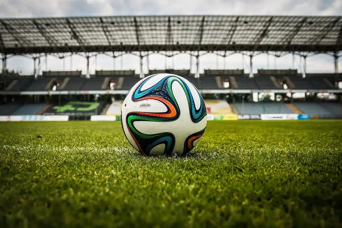 due calciatori in silhouette che si abbracciano su un campo con uno stadio sullo sfondo