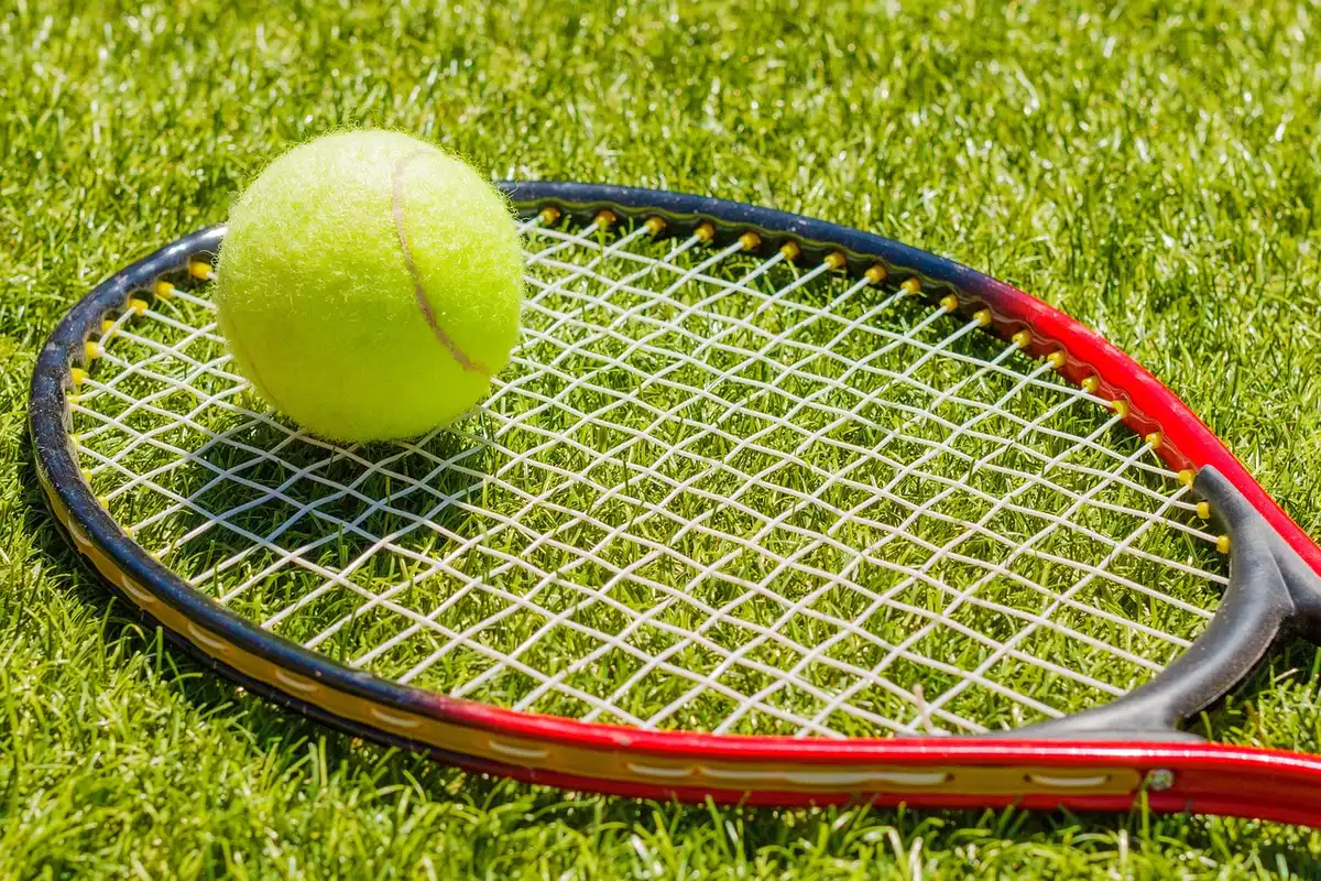 Palla e racchetta vicino alla rete su un campo da tennis vuoto, stadio sullo sfondo