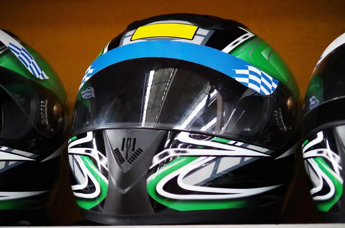 Casco da kart con numero 93 su un banco in pit lane, guanti e clipboard sullo sfondo