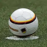 Fascia da capitano appoggiata su una panca nello spogliatoio con scarpe da calcio