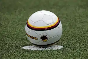 Fascia da capitano appoggiata su una panca nello spogliatoio con scarpe da calcio