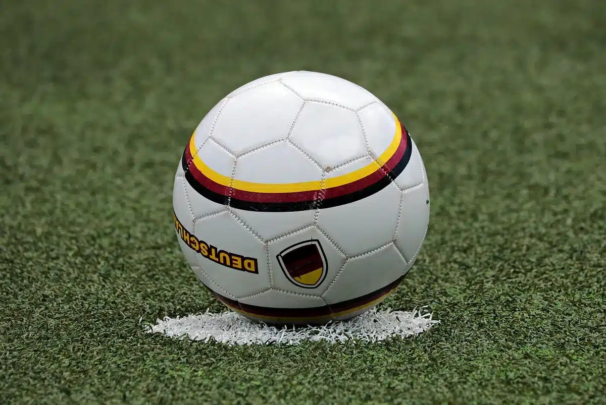 Fascia da capitano appoggiata su una panca nello spogliatoio con scarpe da calcio
