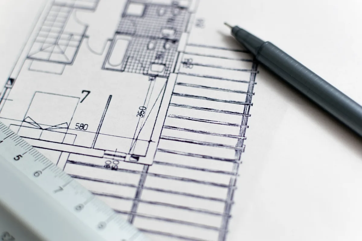 Planimetria del cantiere su tavolo con persone che discutono il cronoprogramma