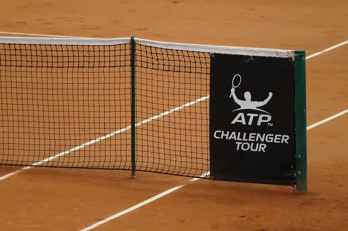 Silhouette di due tennisti su campo in cemento, palla vicino alla rete